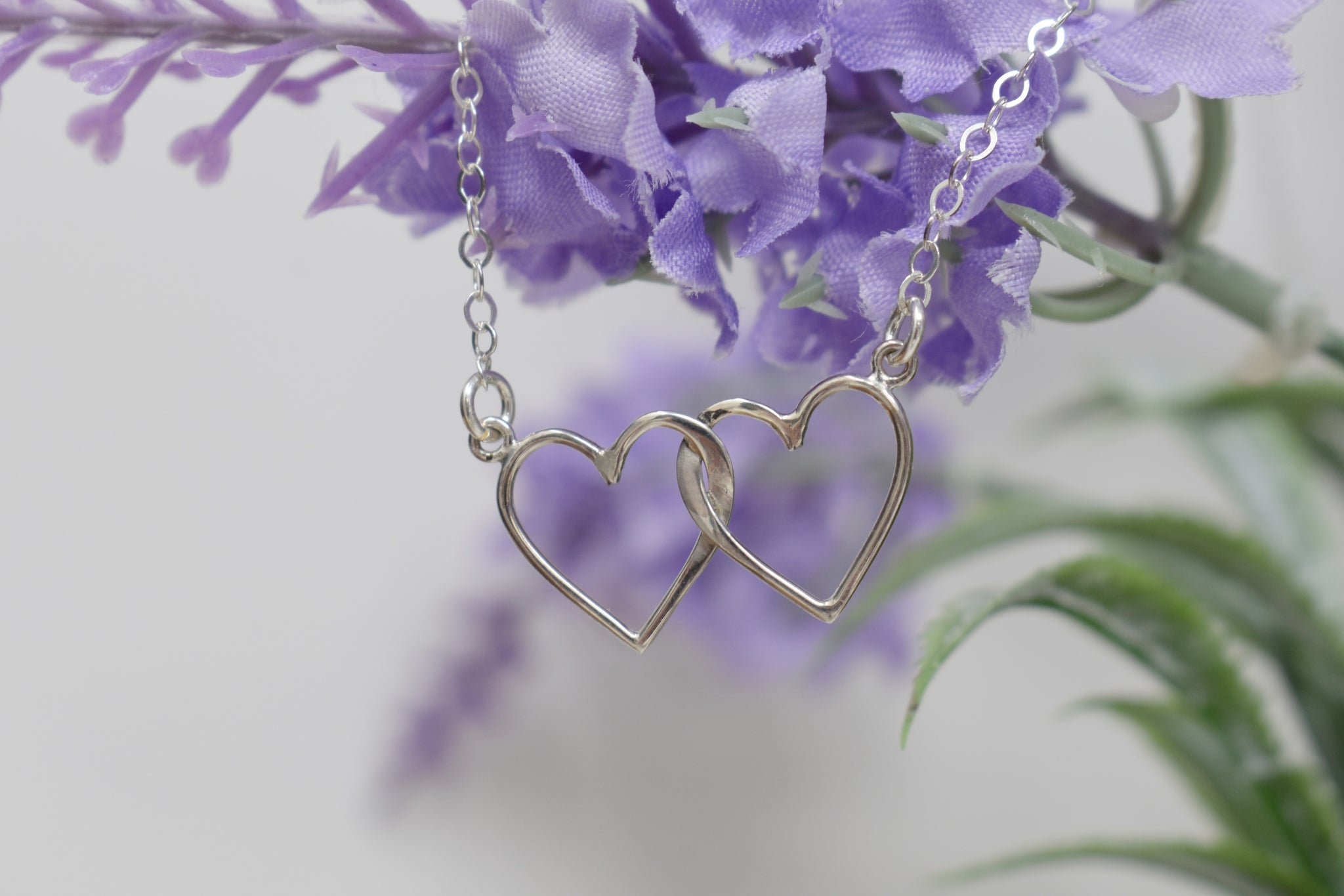 Two Interlocking Hearts in Sterling Silver Suspended on an 18 Inch Sterling Silver Split Chain.